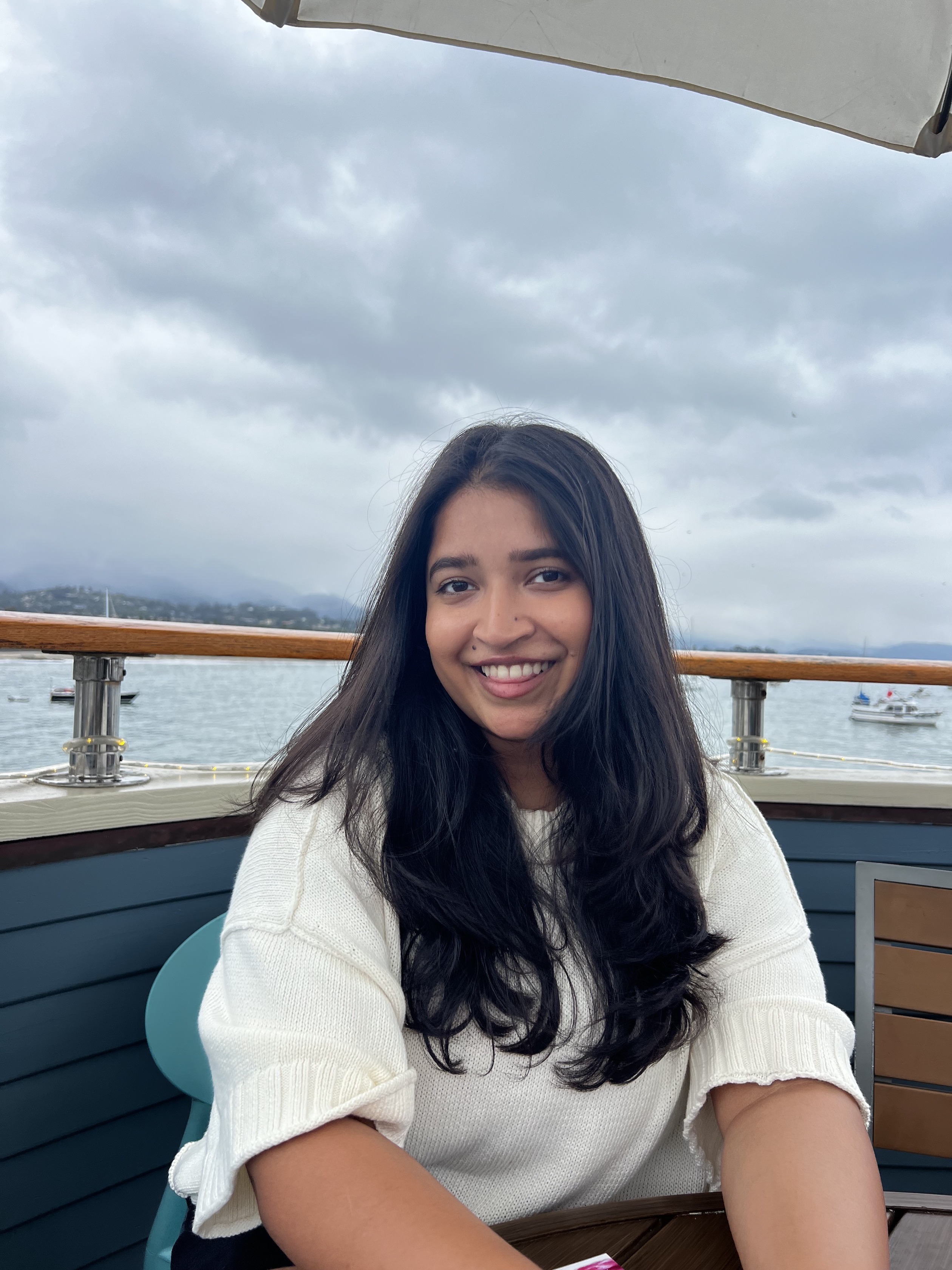 Picture of Anusha smiling and a harbor in the background