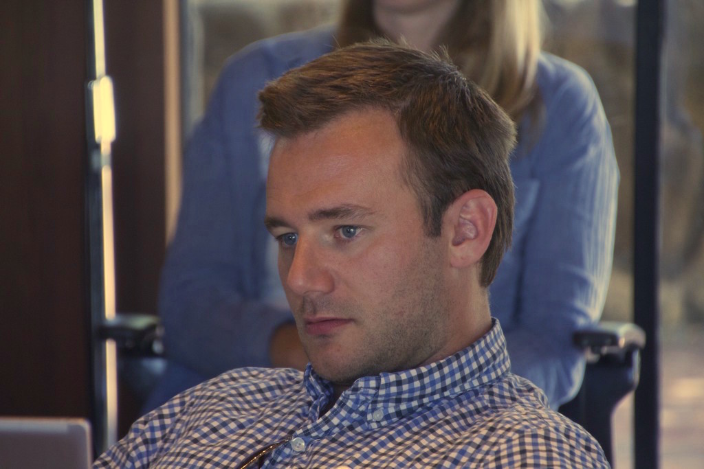 Picture of Protzko with a serious face looking off into the distance. He is wearing collared shirt.