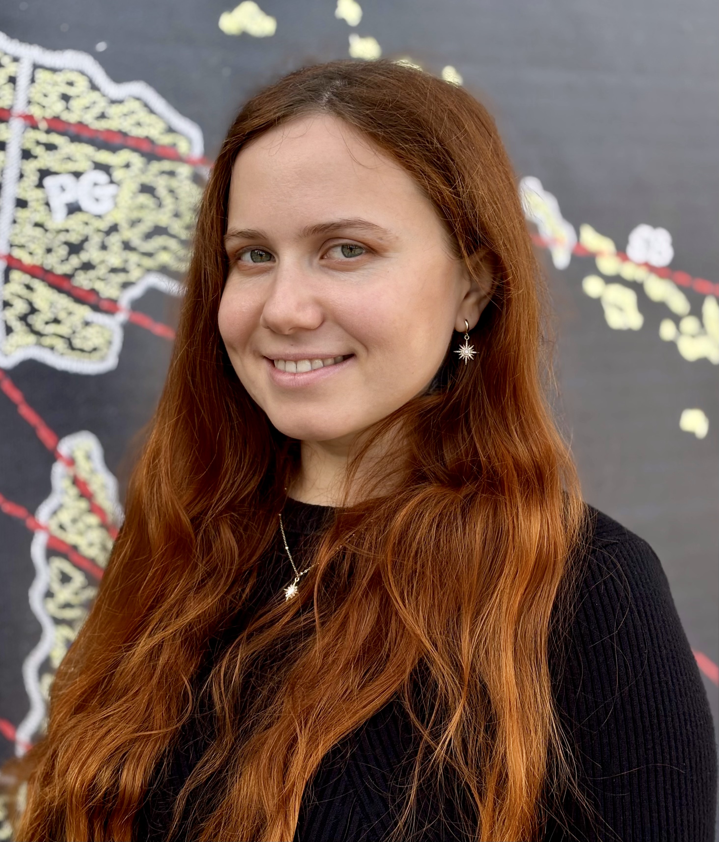 Headshot of Nadu with chalkboard art in the background