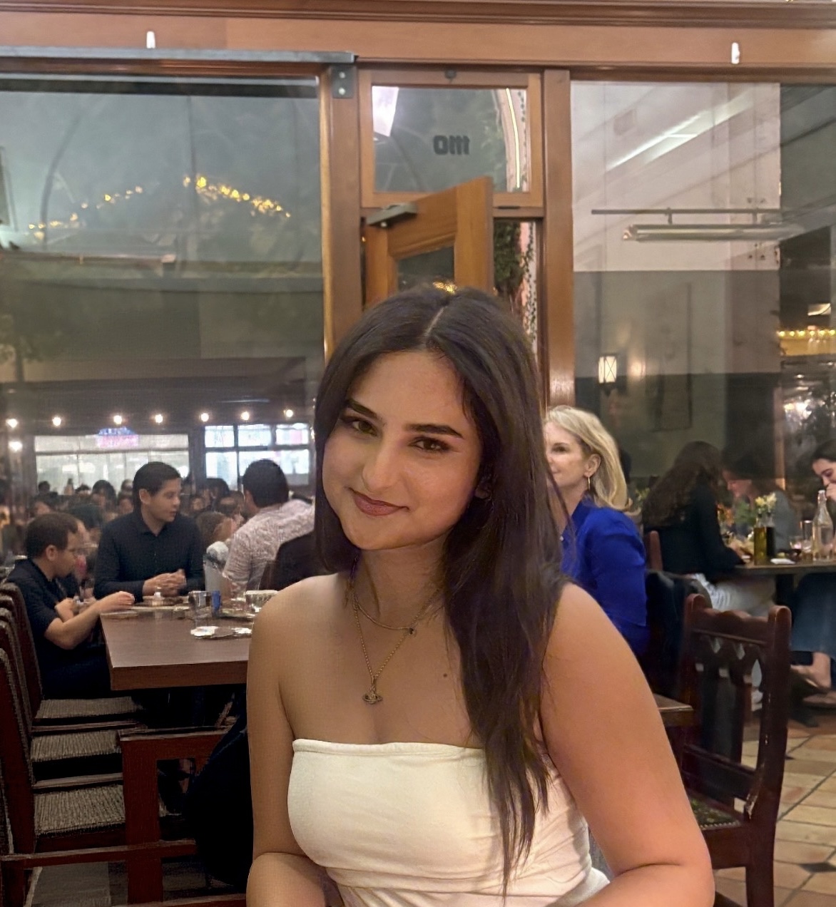 Picture of Kate sitting at a restaurant with people in the background eating.