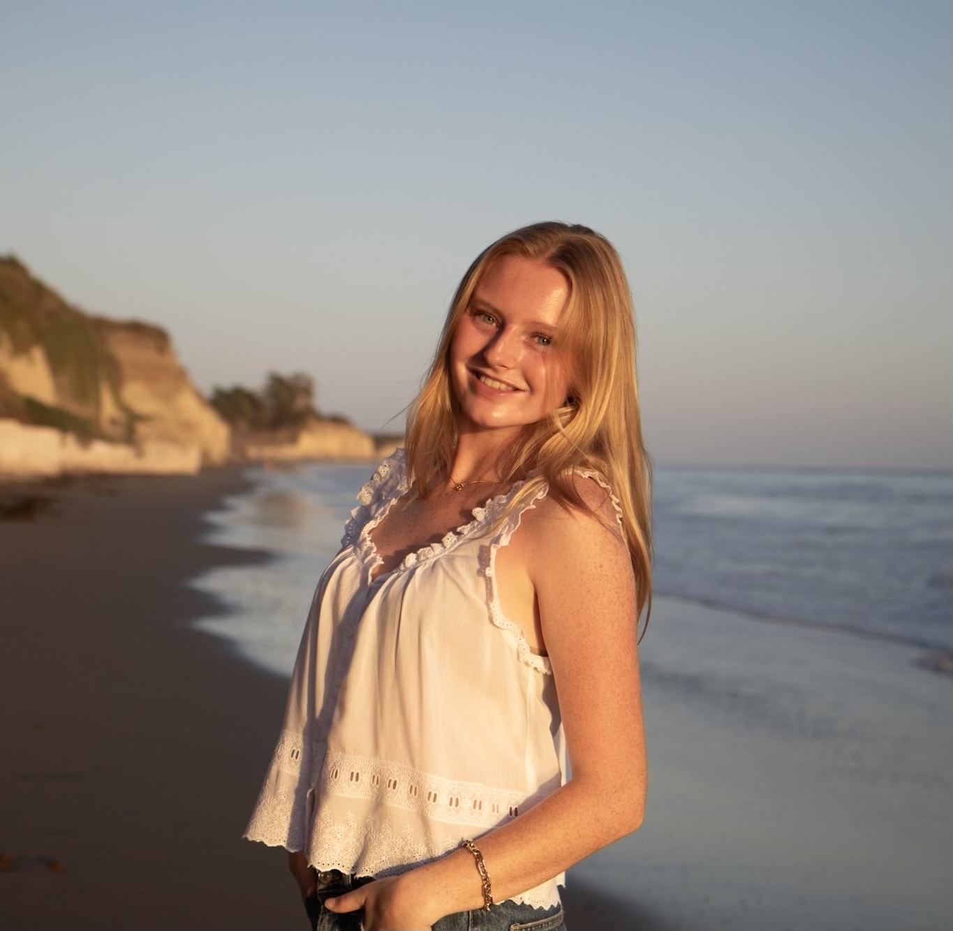 Picture of Astrid smiling with the beach in the background.